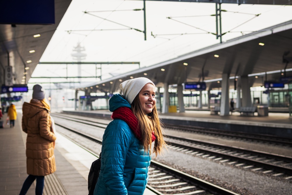 People,Waiting,For,Train,At,Railroad,Station.,Smiling,Young,Woman